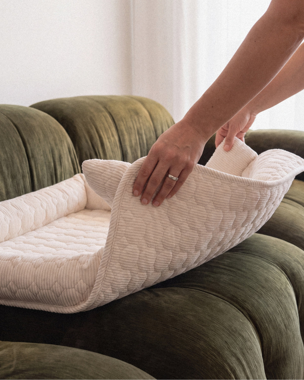 Handen pakken de Cloud Sofa Cover in één beweging van de bank om hem in de wasmachine te doen